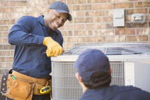 smiling-HVAC-technician-working-on-an-AC-outdoor-unit